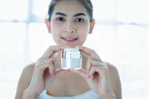 A beautiful woman asian using a skin care product, moisturizer o