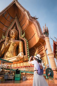 Tourist Woman Having Fun While Sightseeing in The Temple, Asian Woman Relaxing and Enjoyment While Photographing Statue of Buddha With Art Ancient Architecture in Religion Worship. Travel Exploring