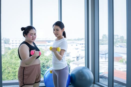 Asian Fat woman and trainer work out in the fitness class and The trainer recommends exercise for weight loss for obese women