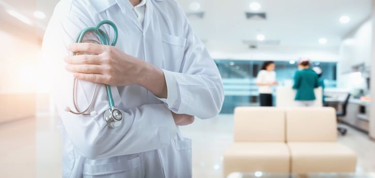 Medical Doctor Standing With Stethoscope and Arm Crossed Posing on Health Examination Patient Room Background, Close Up of Physician Doctors at Examining Patients Clinic Hospital. Health Insurance
