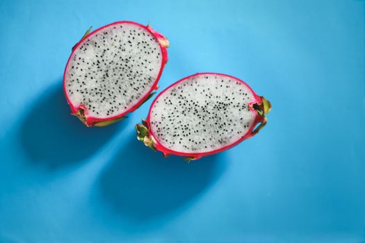 Fresh sliced dragonfruit or pitaya against a bright blue background