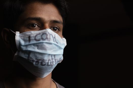 Young man with wearing I Can't Breathe inscription on medical face mask with copy space. Cooncept of Protest about Human Right of Black People in U.S. America