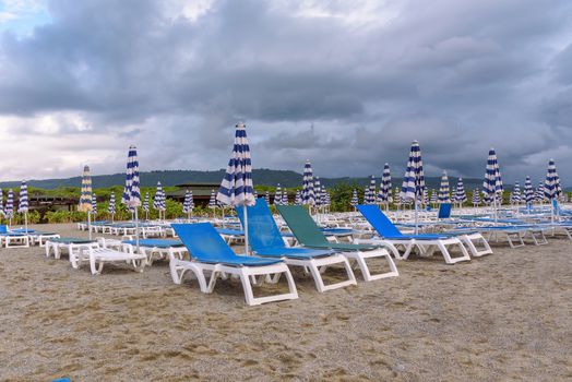 Sunbeds and umbrellas on the calabrian beach on the cloudy evening