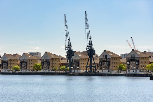 Port cranes and houses at Royal Victoria Dock in London, UK