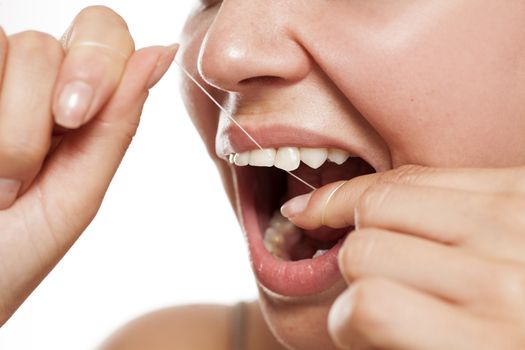 woman cleans her teeth with a dental floss