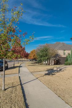 Typical front porch entrance of new suburban houses with parked car on colorful fall street outside Dallas, Texas, USA