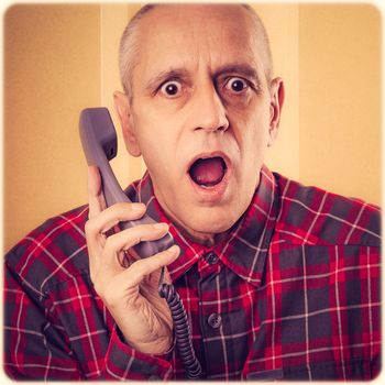 A senior man surprised by an incredible new on home phone