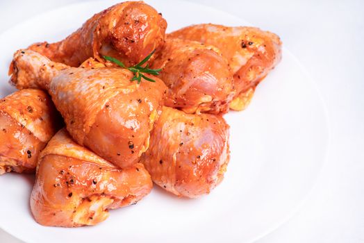 Chicken legs in a red marinade on a white plate. Top view. Chicken meat close-up.Dietary meat. Cooking.Raw marinated chicken legs for grill and bbq.Isolate.