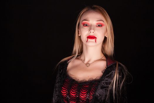 Evil vampire woman with blond hair over black background