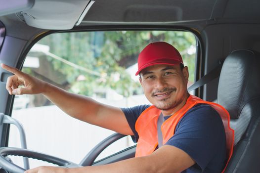 An Asian man was smiling happily at the yellow truck. He has a career as a transport driver. The transportation business never stops. It must be driven and traveled all the time.
