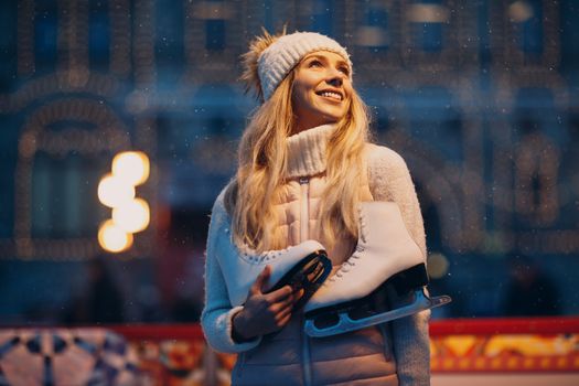 Young smiling woman with skates on the ice rink