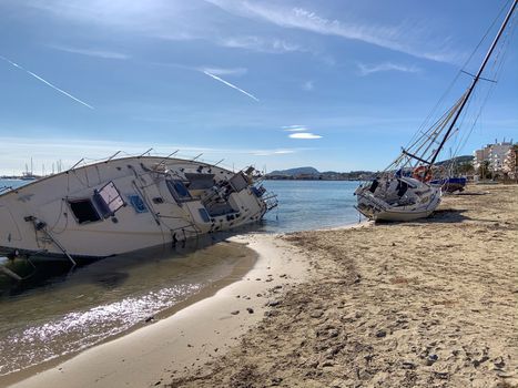Several boats stranded on the beach after a storm. On a sunny day with few clouds. sailboat