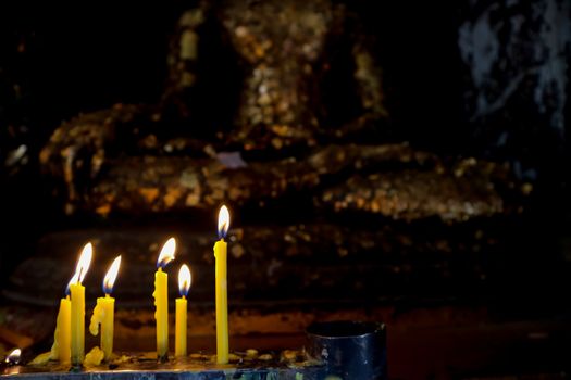 candle and flame in buddist temple gold buddha background
