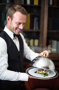 Handsome waiter serving meal