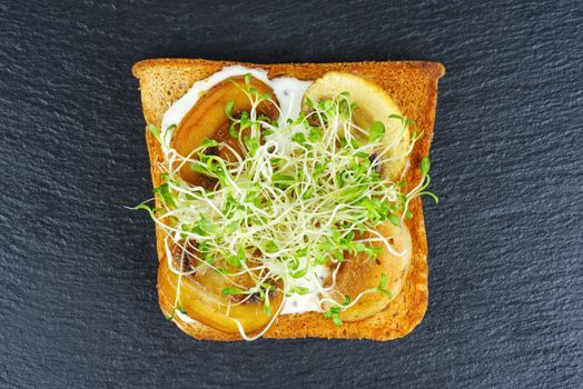 Green alfalfa sprouts, grilled portabello mushrooms on toasted slices of wholegrain bread on black stone