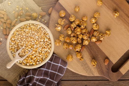 Corn kernels in wooden plates and popcorn with Caramel and almon