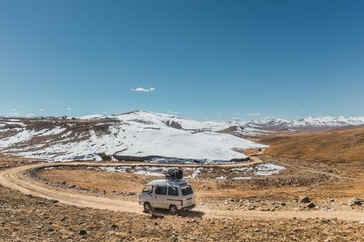 Local bus with luggage running along unpaved road at Deosai plains