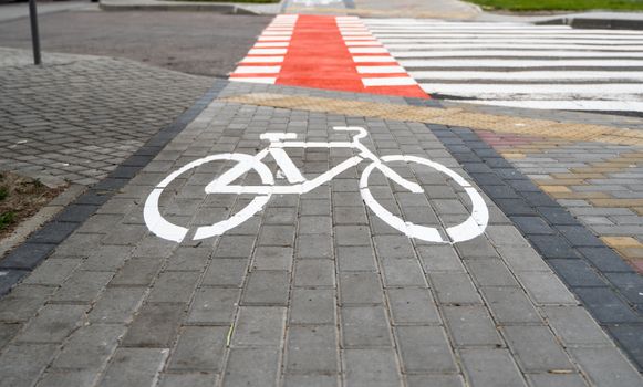 Cycling path with a symbol of bike on a ground through avtomobile road. Bike path in a modern city.
