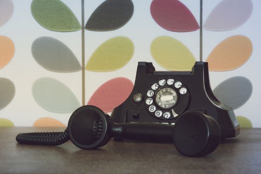 Old retro and vintage phone off the hook against colorful wallpaper