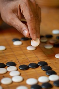 Go board game playing. A competitor is placing a marble piece on