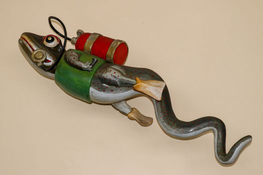 Statue of gecko with diving equipment on the wall of diving center. 3D gecko as a diver. Lizard figurine with green jacket, red diving tank and yellow fins. A funny accessory in the diving base area.