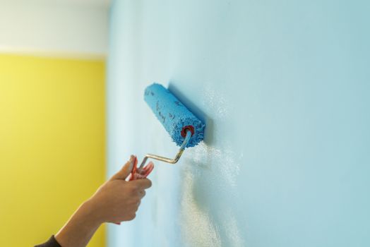 Workman painting the wall in blue.