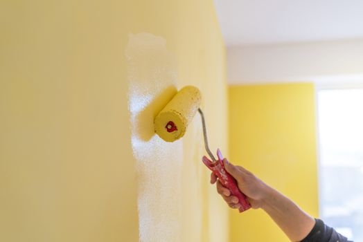 Workman painting the wall in yellow.