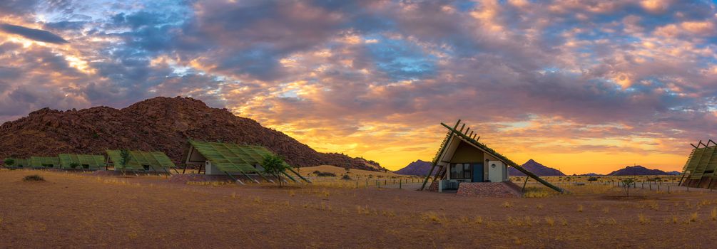 Sunrise above small chalets of a desert lodge near Sossusvlei in Namibia