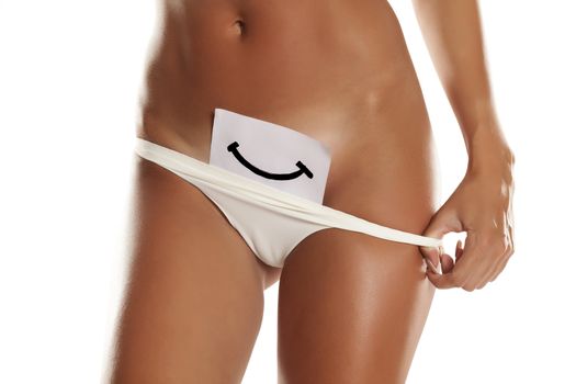 Woman with panties cowers her vagina with smile drawn on sheet