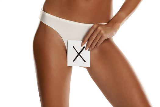 Woman with panties cowers her vagina with X sign drawn on sheet 