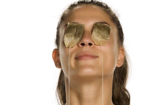 woman posing with tea bags on her eyes
