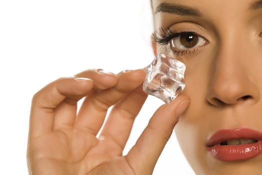 woman holding ice cube under the eye