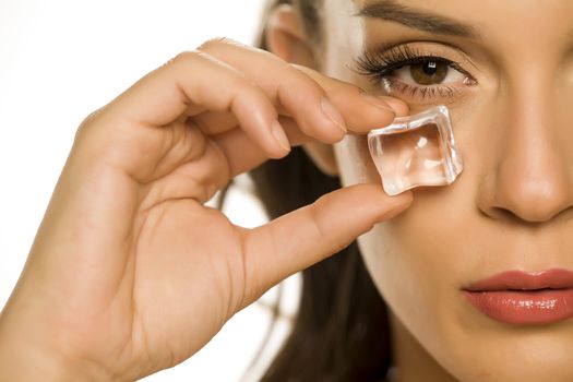 woman holding ice cube under the eye