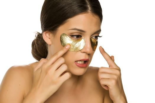 Young beautiful woman posing with golden patches under her eyes on white background