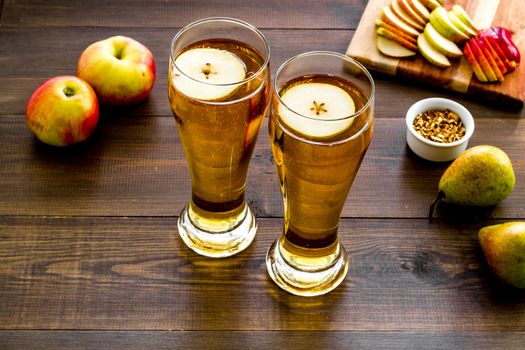Glasses of beer with apple and peer on wooden desk