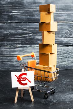 A shopping cart loaded with boxes and a sign with a euro symbol down arrow. Decrease in income from sales of goods and retail. Fall in purchasing power. Price reduction, discounts