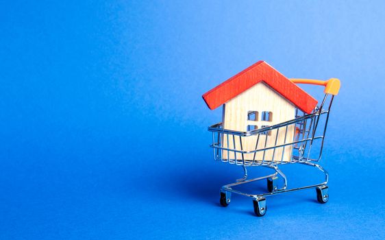 Wooden house in a Supermarket trading cart. The concept of buying a house or apartment. Affordable housing. Profitable and cheap loans for real estate. Buying a home. Mortgage and loan. Place for text