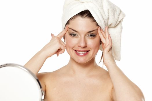 Young happy woman with towel on her head, tightens her face with