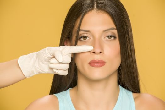 Doctor's hands touching the nose of a young woman