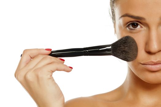 Young woman applying a powder foundation with brush