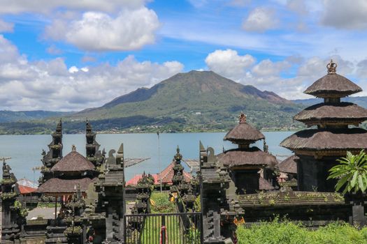 Hindu altar above valley in Kintamani area. View of the volcanic caldera Batur and the lake. In the background rises Mount Batur. Sunny day with azure blue arch and white clouds. Nature background.