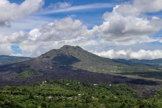 Volcano landscape with lava fields, pine tree forest and farms and houses on the slopes. Kintamani is a village on the western edge of the larger caldera wall of Gunung Batur in Bali, Indonesia.