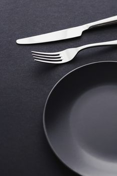 Empty plates and silverware on black background, premium tableware for holiday dinner, minimalistic design and diet