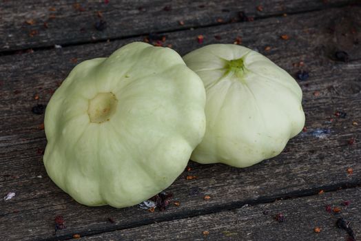 Two pattypan squash lie on the old wooden table in the garden
