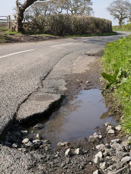 Unrepaired surface damage to tarmac on a rural road