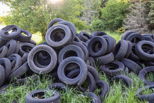 Damaged and worn old black tires on a stack. Damaged and worn ol