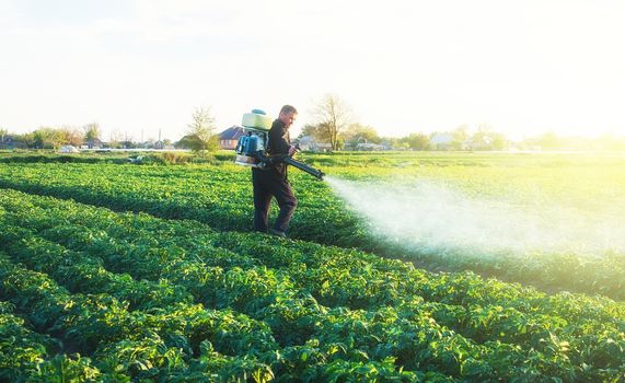 Farmer spraying a chemical copper sulfate on a potato plantation to protect against fungal infections. Agribusiness, agricultural industry. Crop protection. Modern technologies in agriculture