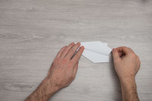 How to make origami paper airplane step by step photo instruction on wooden table with arms. Step 10