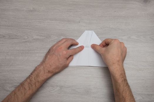 How to make origami paper airplane step by step photo instruction on wooden table with arms. Step 7