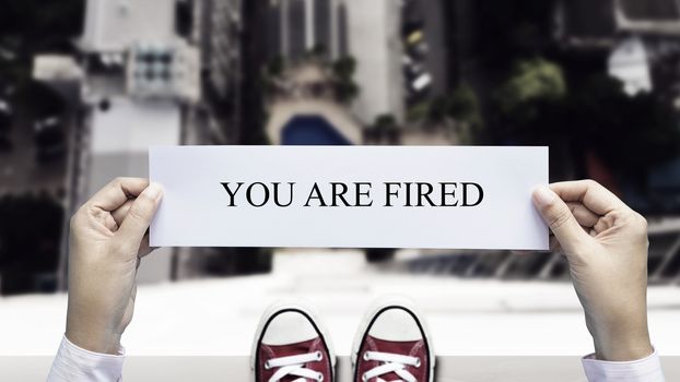 stress business man decide to commit suicide by jump from high building with paper "you are fired" in hand. dismiss from employment and employee lay off problem